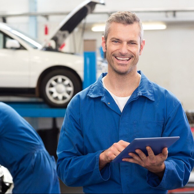 Smiling mechanic using a tablet pc at the repair garage-1